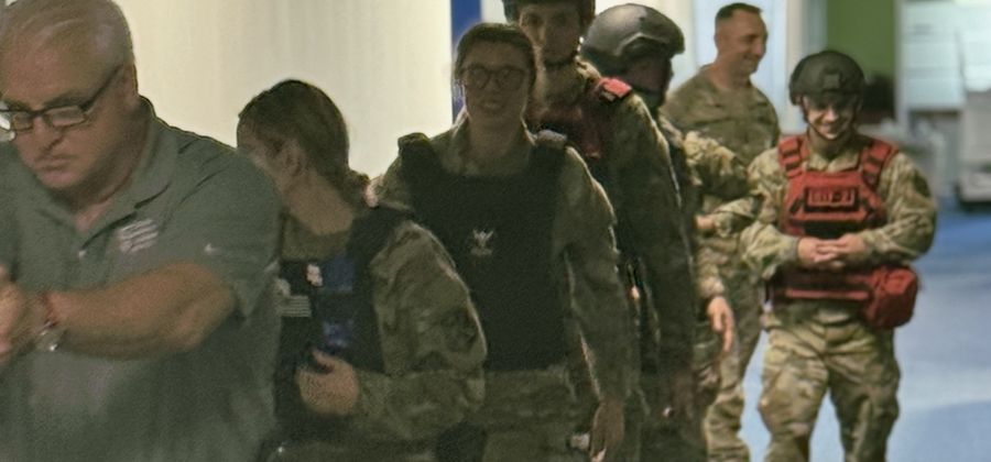 Rescue Task Force team in helmets and plate carriers moving down a hallway in a training stack