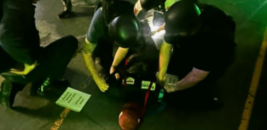 Responders in helmets treating a casualty during a low-light scenario